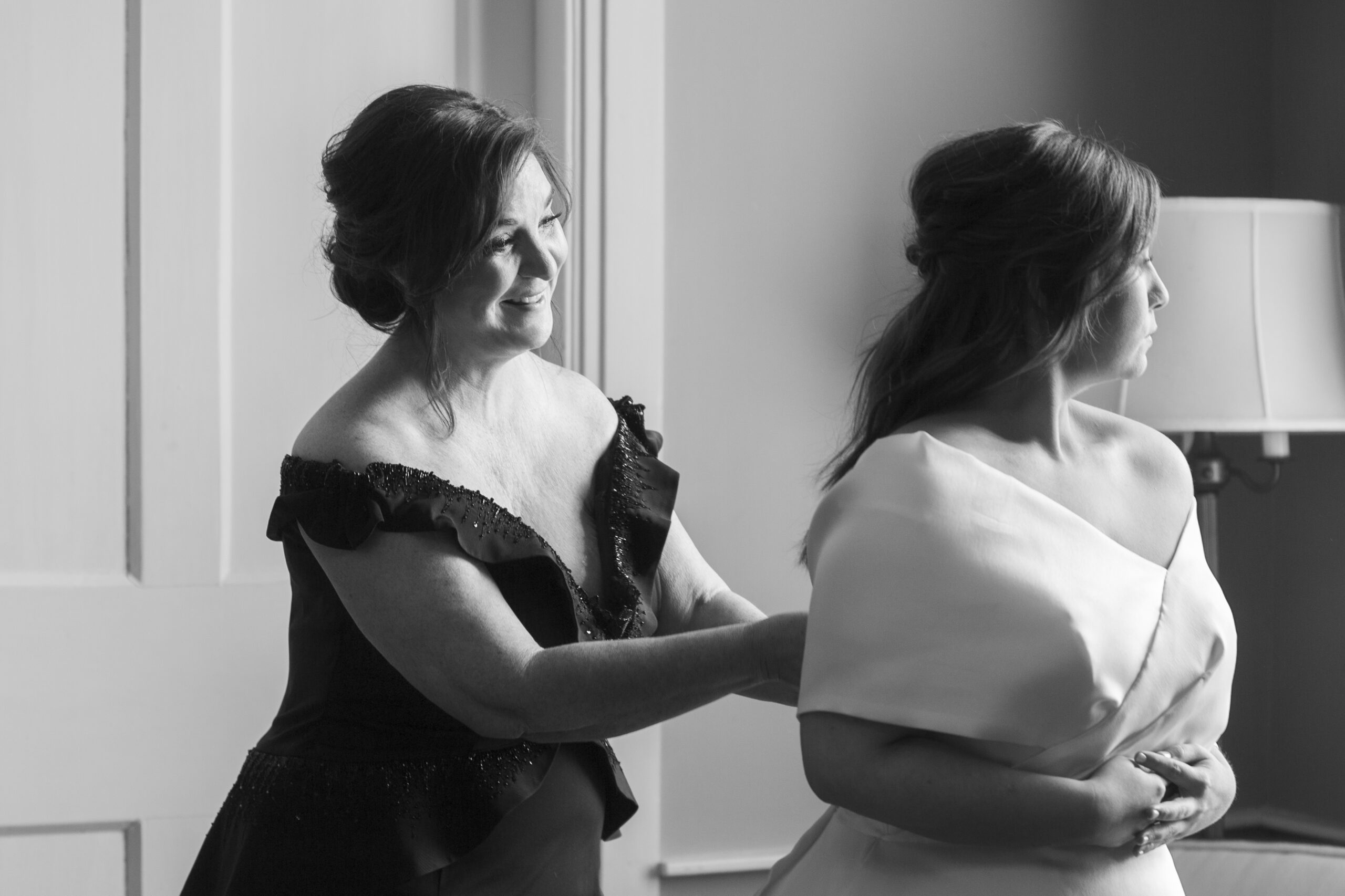 The mother of the bride helps the bride into her wedding dress at Pursell Farms.