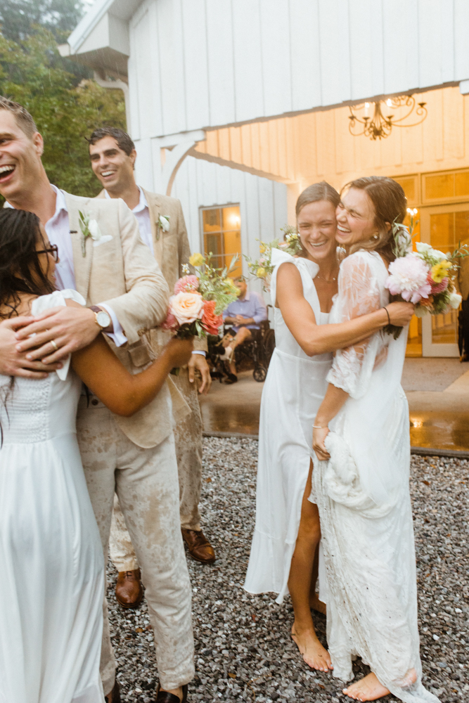 The wedding party celebrates together in the rain.