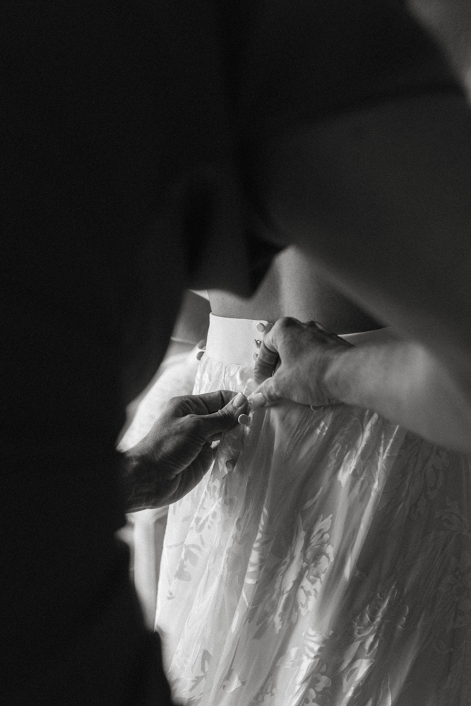 The mother of the bride helps button the dress of her daughter's bridal gown in Alabama.