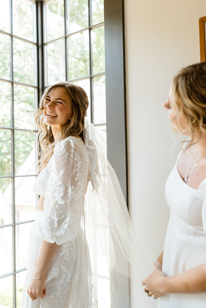 The bride laughs as she puts on her Alabama wedding dress.