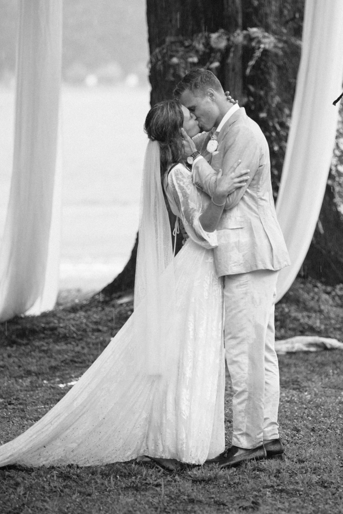 The bride and groom kiss in front of the old oak tree.