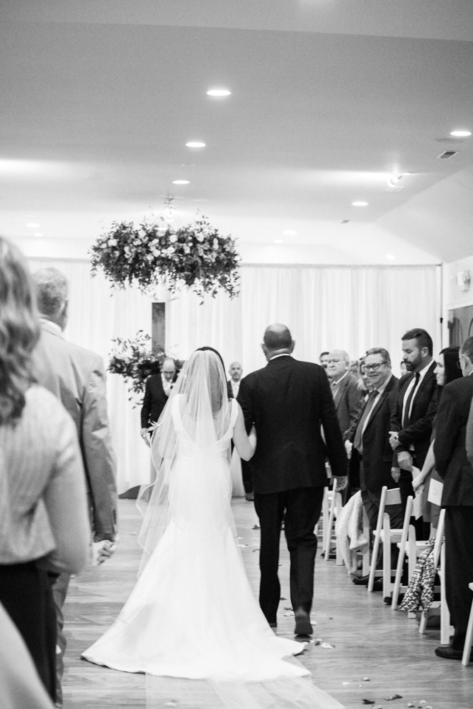 The father of the bride walks the bride down the aisle at this Southern wedding ceremony.