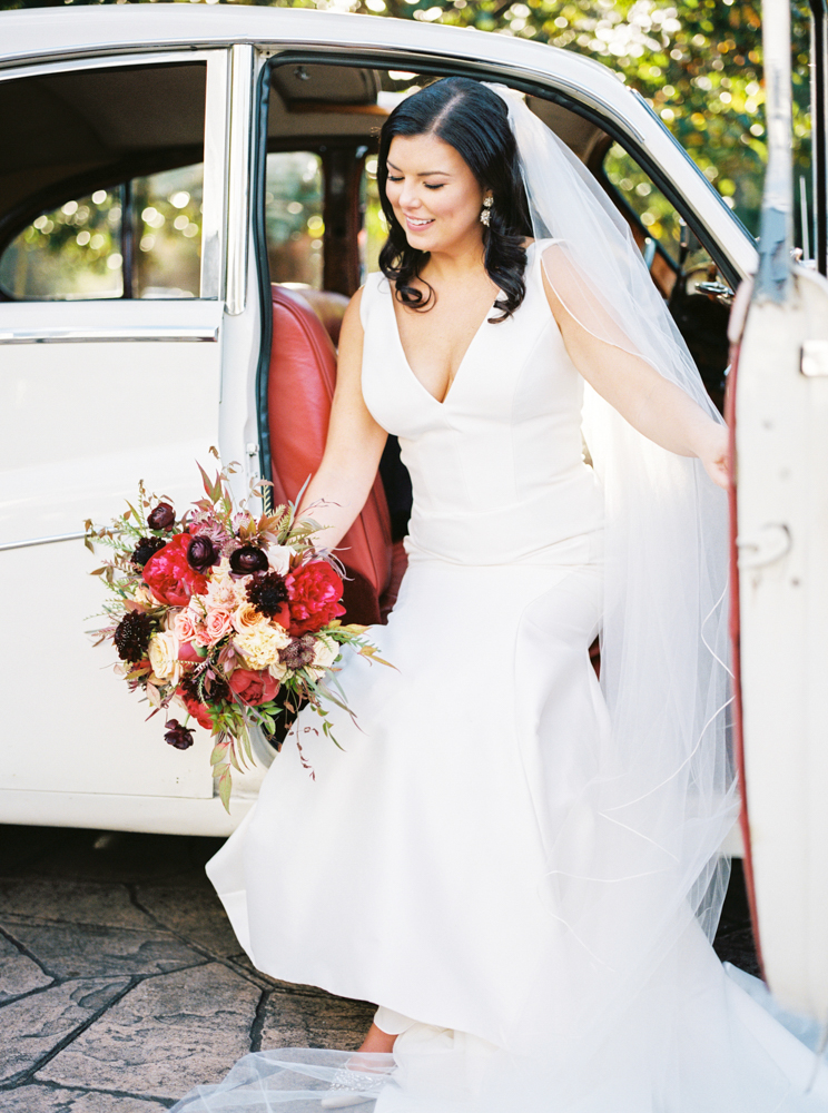 The bride is photographed with her autumn bouquet by Piper Vine as she exits the car.