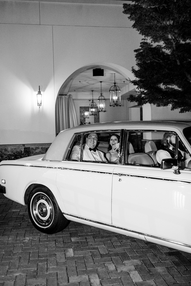 The bride and groom are driven away in a classic car from their wedding at Grand Bohemian Hotel Mountain Brook.