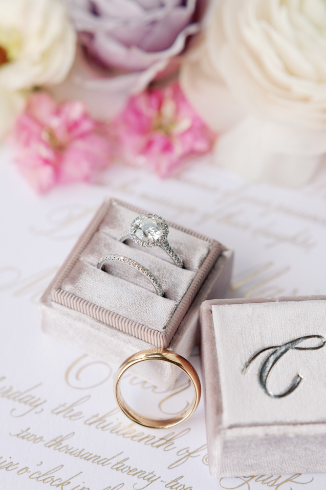 The wedding rings are photographed in a lilac velvet ring box.