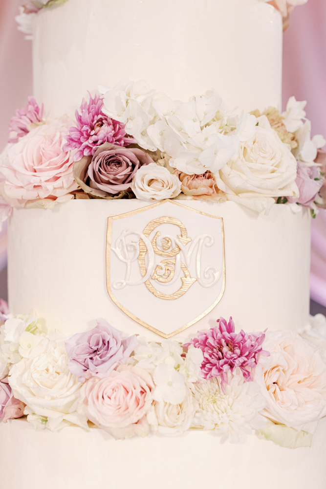 The wedding cake is adorned with flowers and a custom monogram at the Birmingham wedding.