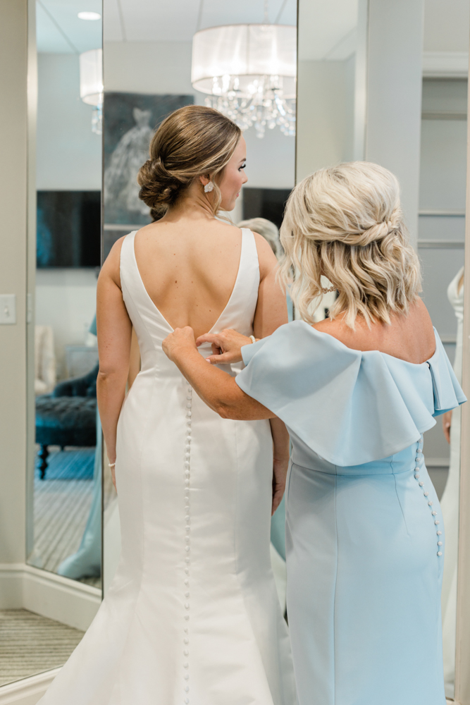 The mother of the bride helps her daughter into her Alabama wedding dress in the bridal suite at Huntsville Botanical Garden.