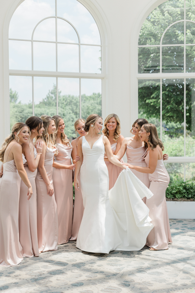 The bridesmaids admire the bride in the atrium of Huntsville Botanical Garden.