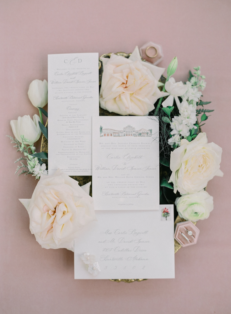 The wedding invitations are photographed in a lay flat style with flowers.