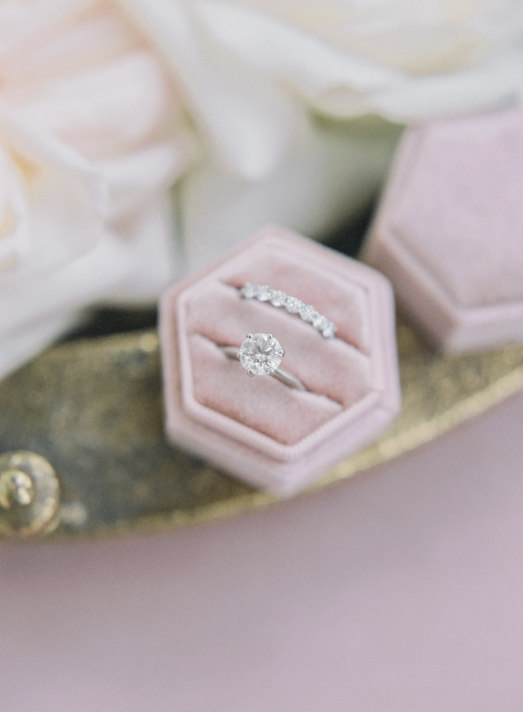 The bride's rings are placed in a pink velvet ring box.