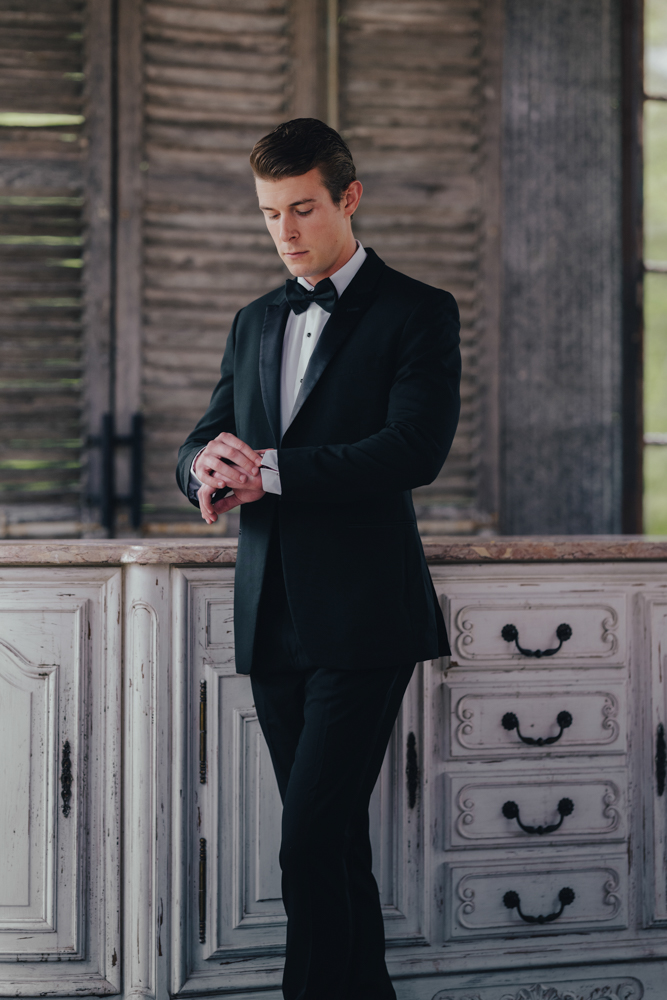 The groom wears a black tuxedo at The Barn at Shady Lane.