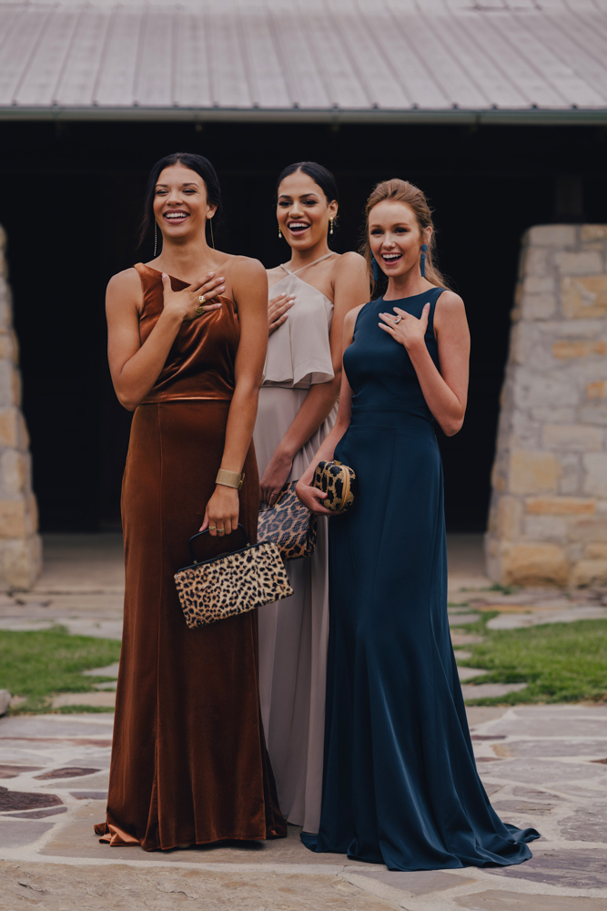 Bridesmaids laugh together in fall bridesmaid dresses outside The Barn at Shady Lane.