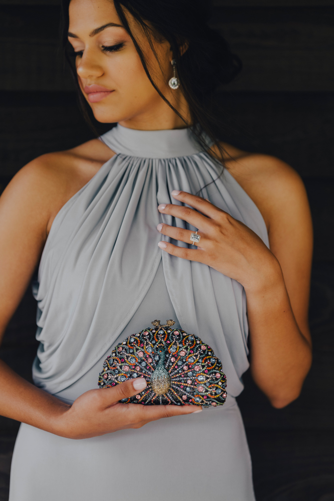 A bridesmaid holds a peacock clutch with a dress from Bella Bridesmaids Birmingham.