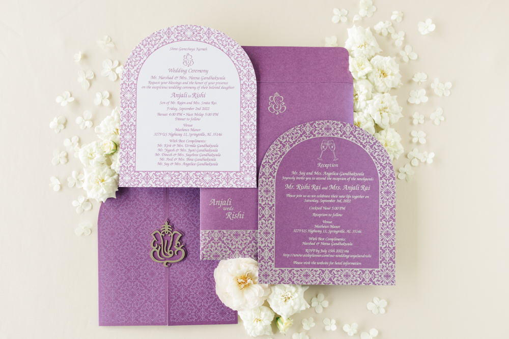 The wedding invitations are styled in a lay flat with white flowers for this Indian wedding in Alabama.