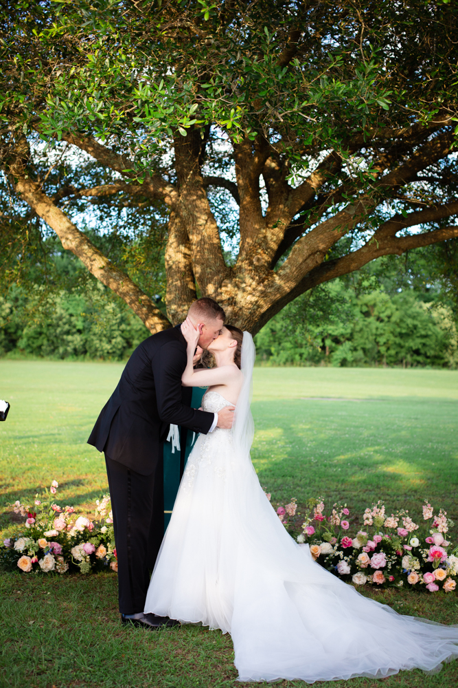 The bride and groom kiss under the tree during their Montgomery, Alabama wedding ceremony.