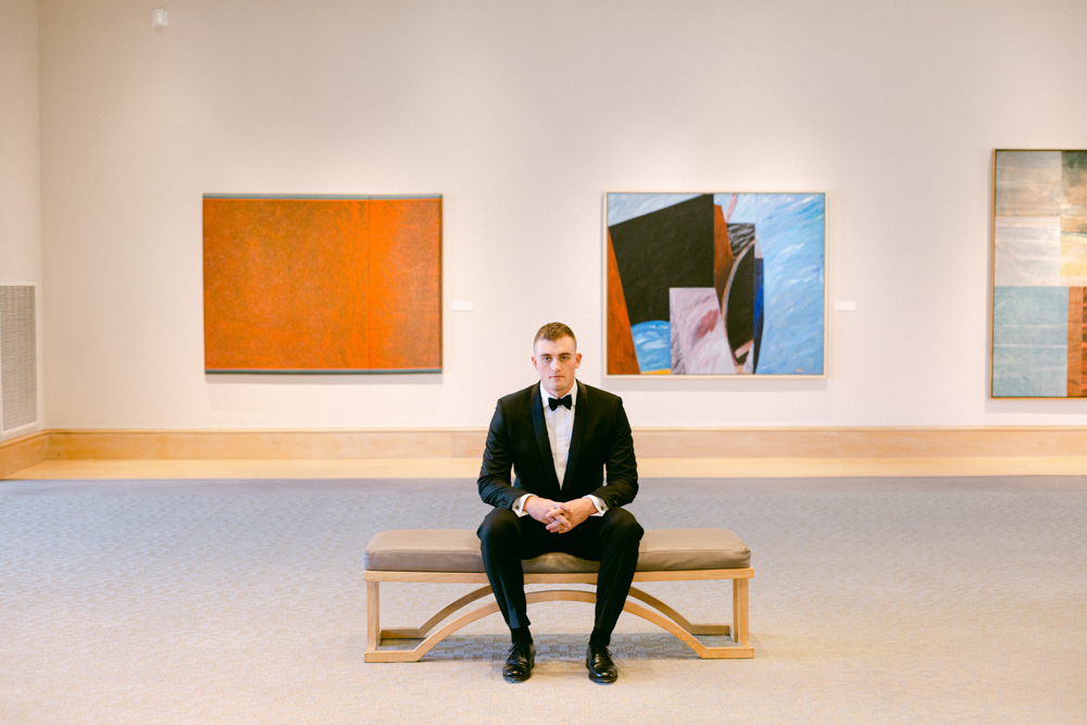 The groom sits in the Montgomery Museum of Fine Arts before a Southern wedding ceremony.