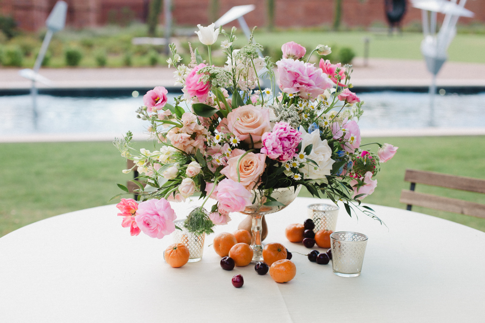 The centerpiece features pink and cream flowers as well as cherries and nectarines for the Southern wedding reception.