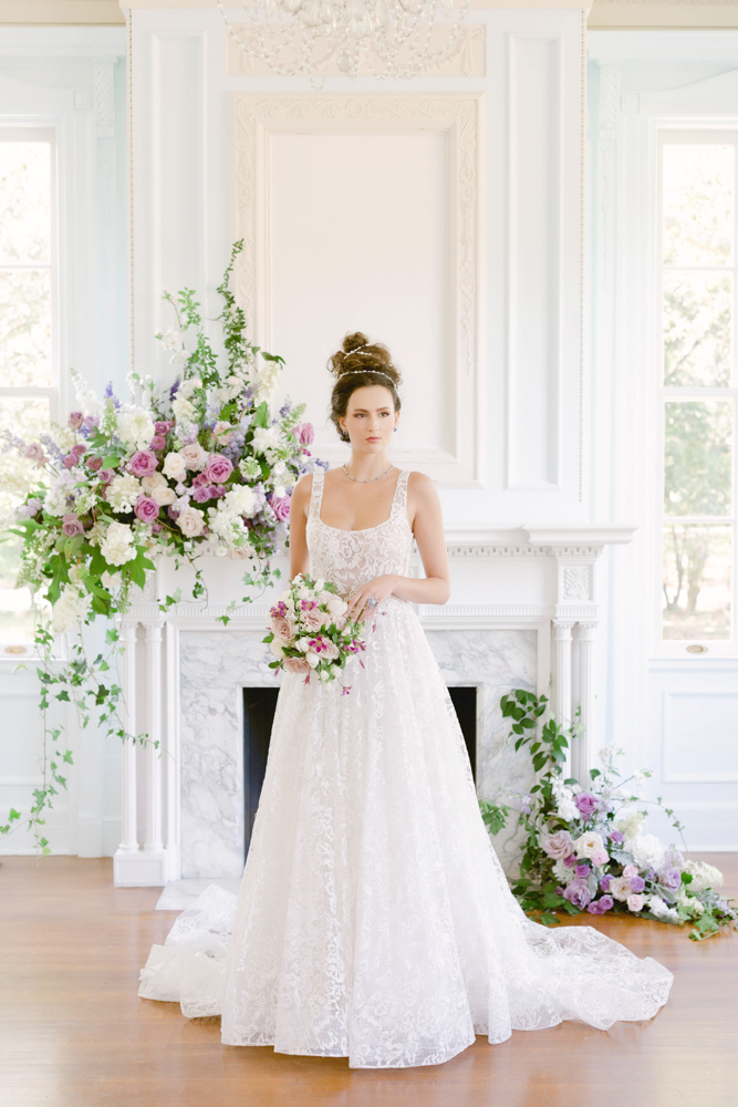 The bride stands in front of the mantlepiece at The 1616 House decorated by flowers from CeCe Designs.