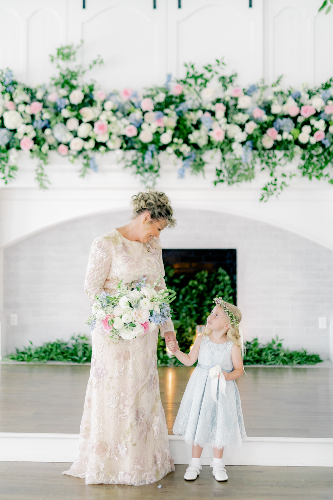 The bride holds the hand of a flower girl before her vow renewal celebration at Oak Meadow Event Center.