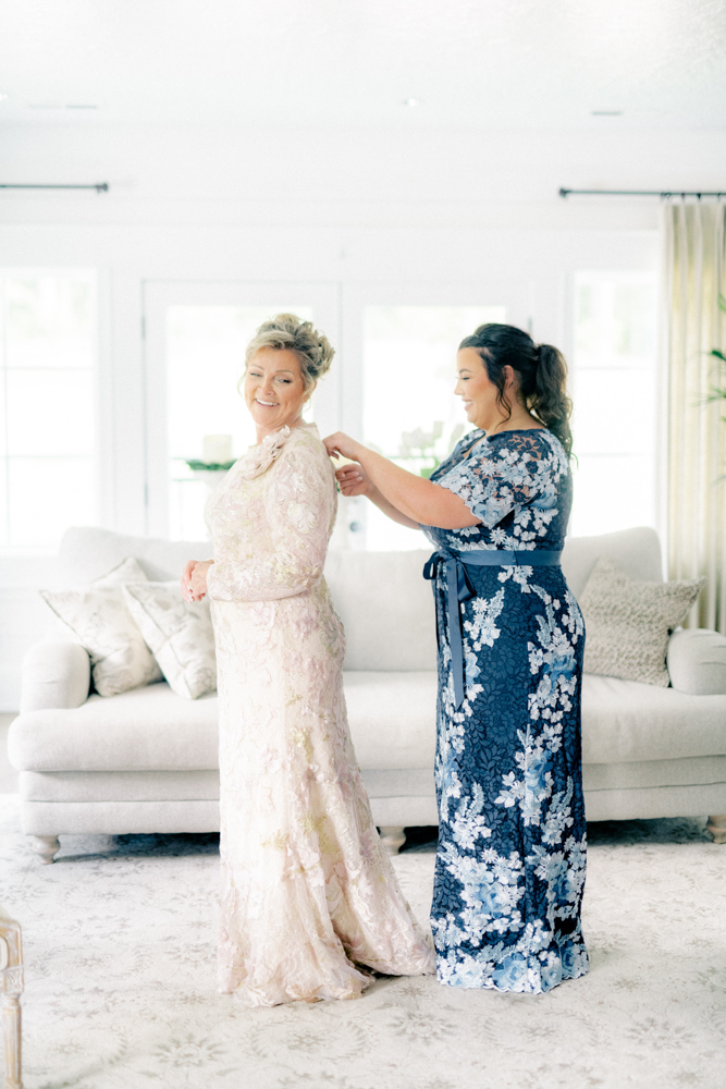 The maid of honor helps the bride into her wedding dress for this Southern wedding.