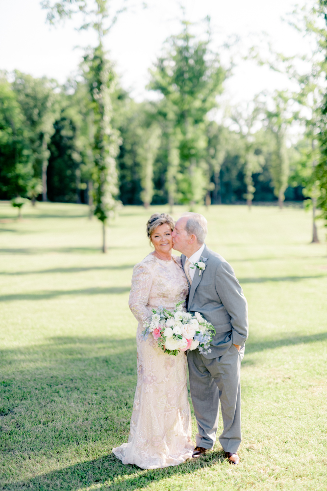 The groom kisses the bride's cheek before their Southern vow renewal celebration.