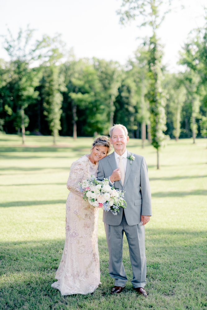 The bride leans on the groom's shoulder in the fields outside Oak Meadow Event Center.