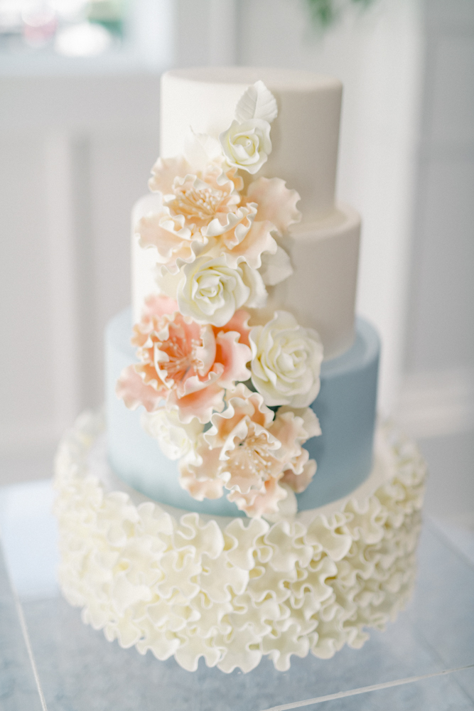 The wedding cake is decorated with pink and white sugar flowers.