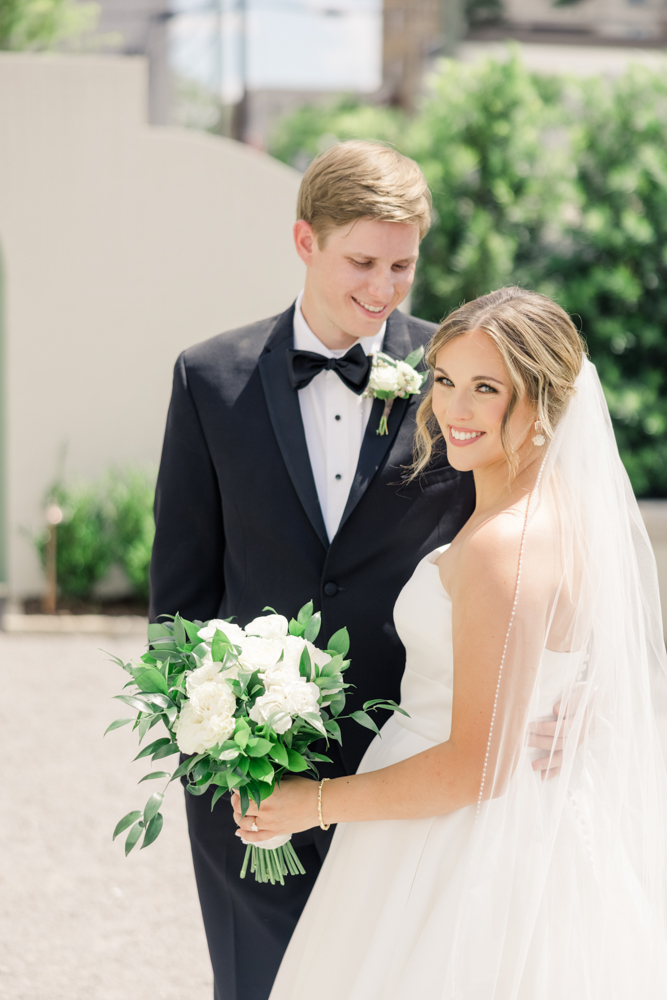 The bride holds her bouquet as the groom stands by her side at The Farrell.