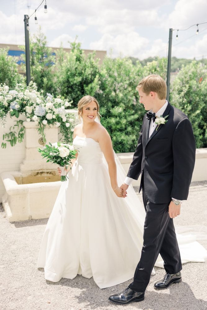 The bride and groom walk together in front of the fountain at The Farrell.