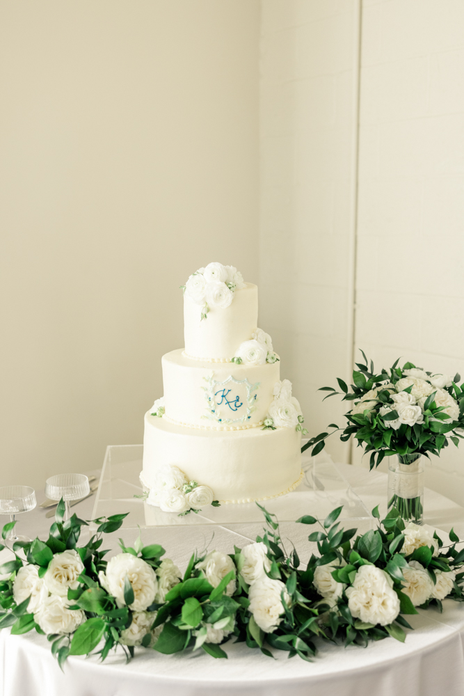 A wedding cake surrounded by classic florals is set at this Southern wedding reception.