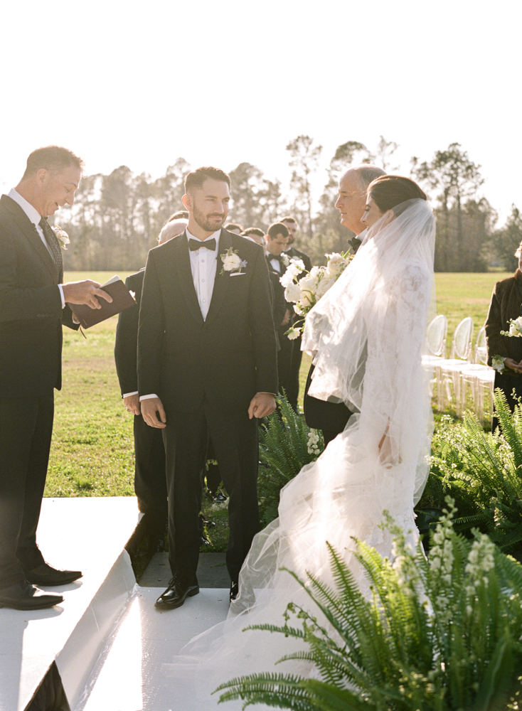 The father of the bride walks his daughter down the aisle for this formal Southern wedding ceremony.