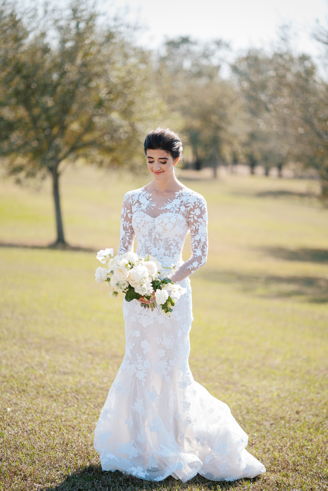 The bride wears a sleeved gown from Ivory & White Bridal Boutique for her Fairhope wedding.