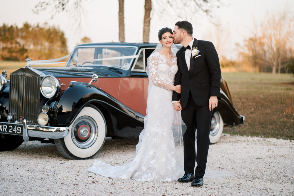 The bride and groom pose in front of their getaway car from Coats Classic Cars.