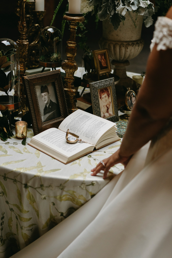 The bride admires family photos on the entrance table for his wedding at B&A Warehouse.