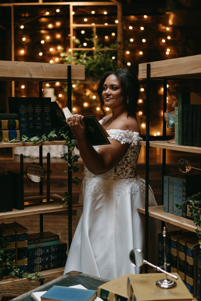 The bride reads a book in the library created at B&A Warehouse for this styled feature by CONFERO.