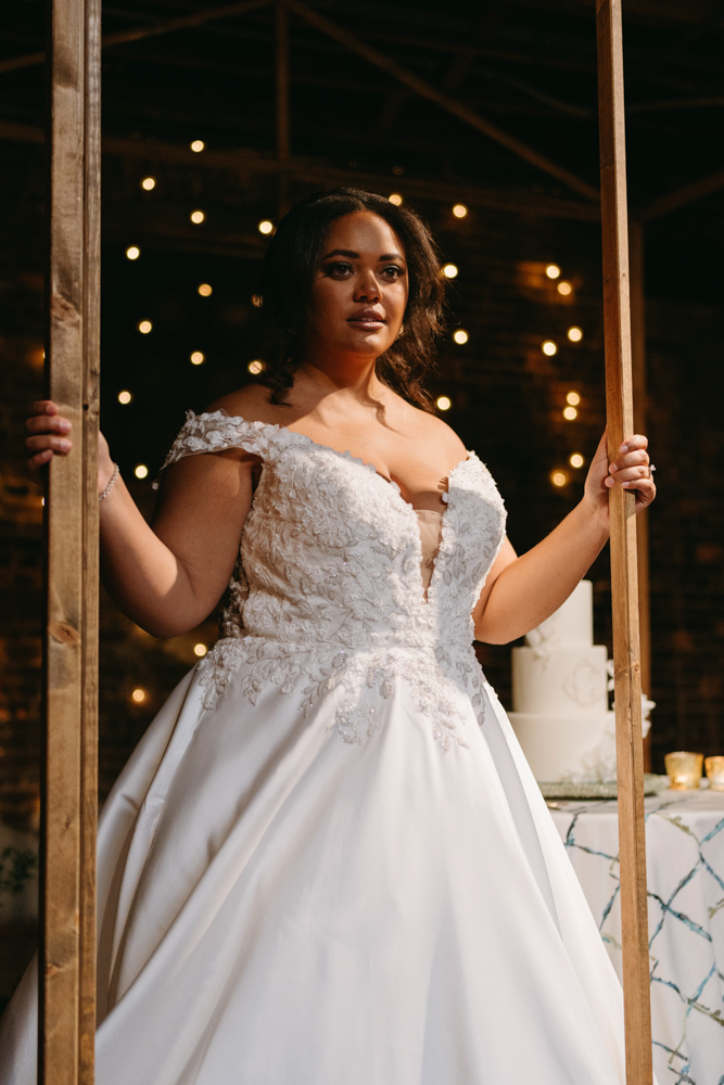 The bride stands in front of her wedding cake for her Southern wedding at B&A Warehouse in Birmingham.