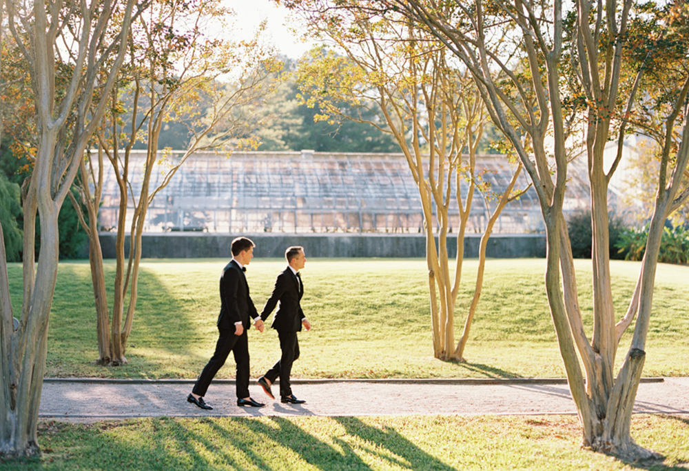 The grooms walk together at Birmingham Botanical Gardens.