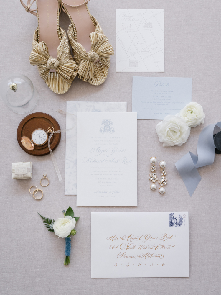 The Southern wedding invitations are styled in a lay flat with the accessories and ribbon.