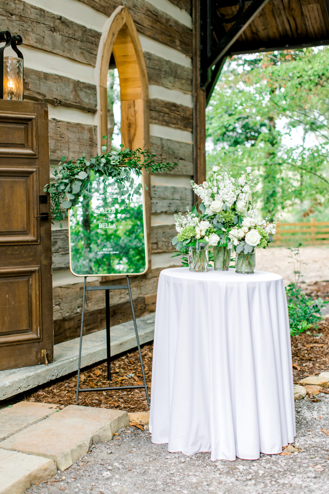 The entrance to the Southern wedding ceremony at Burns Bluff at High Falls features flowers and a custom mirror message.