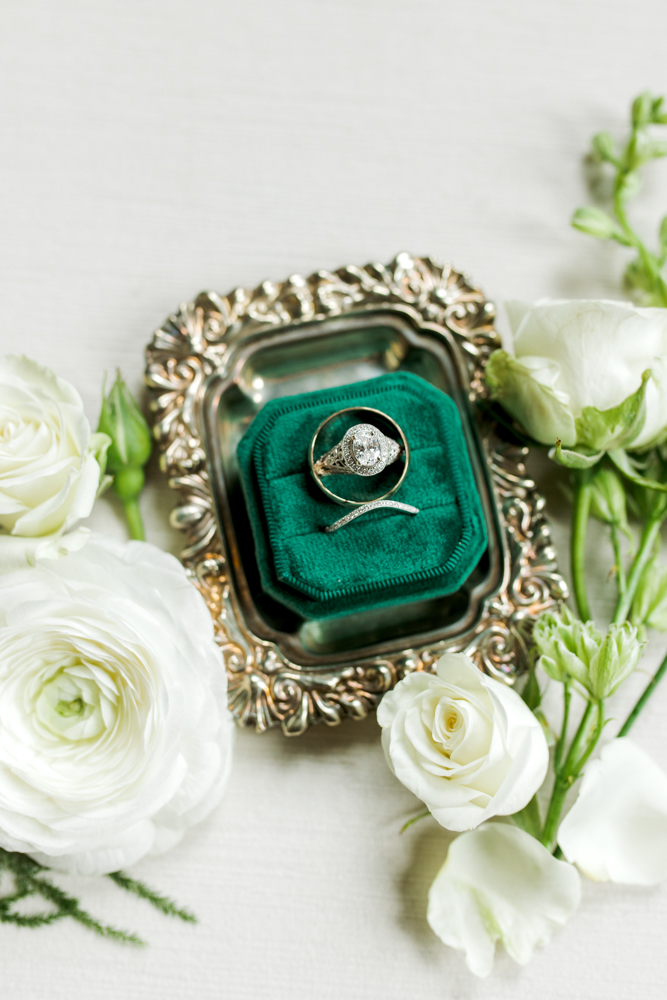 The wedding rings are set in an emerald green velvet ring box.