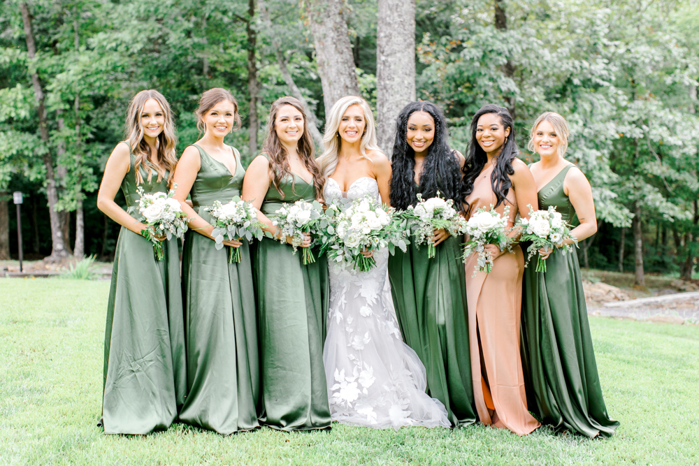 The bride stands with her bridesmaids in green dresses at Burns Bluff at High Falls.