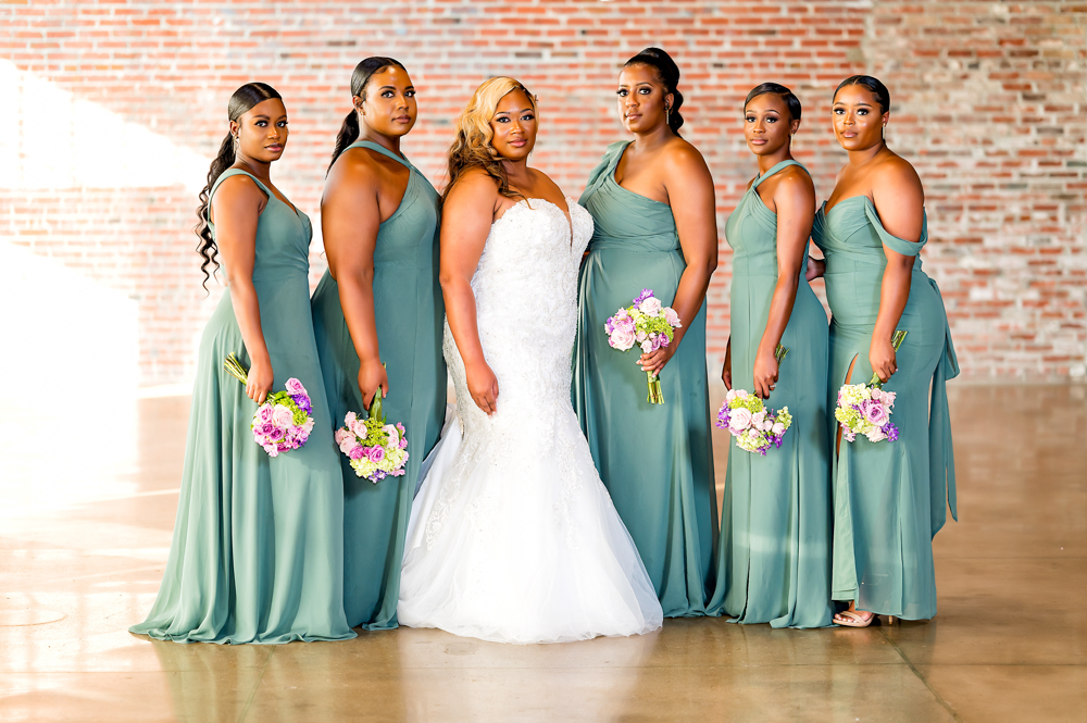 The bride poses with her birdesmaids wearing green dresses.