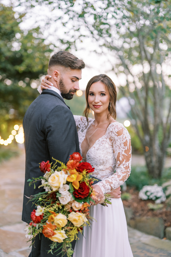 The bride and groom pose together with the bridal bouquet at Otter Creek Farmstead.