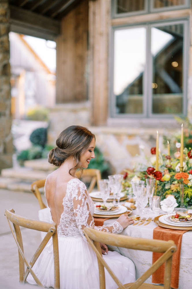 The bride sits at the table for her charcuterie plate at Otter Creek Farmstead.