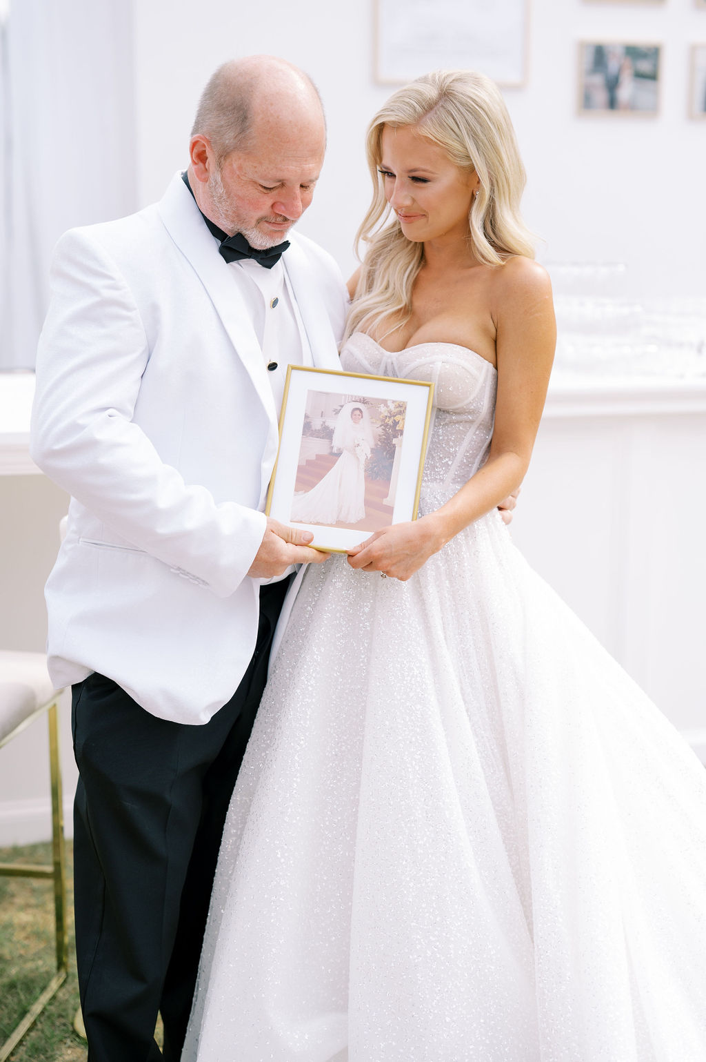 The father of the bride and his daughter hold a family photograph at a Southern wedding.