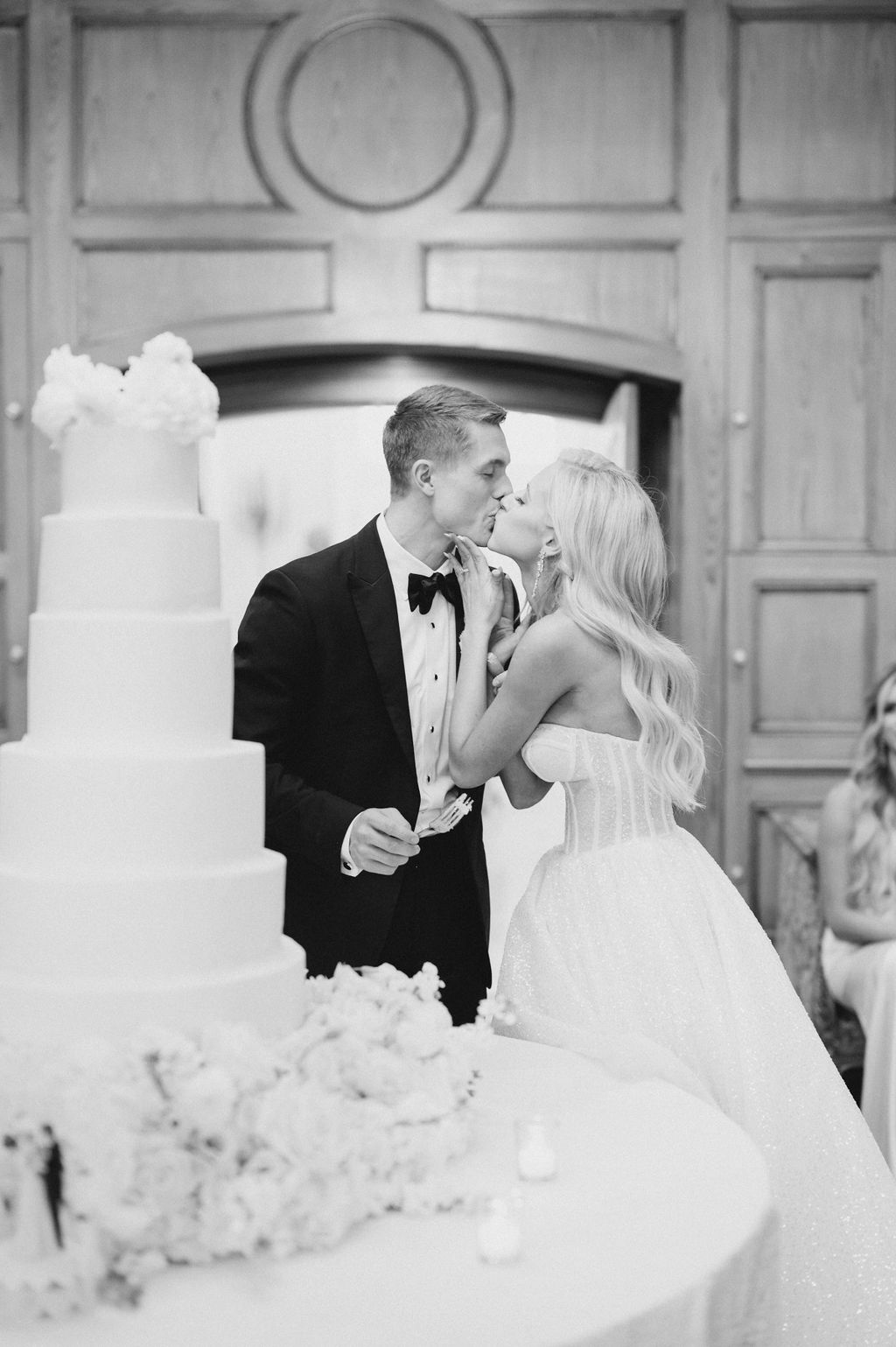 The bride kisses the groom as they cut their wedding cake at Fountainview Mansion.