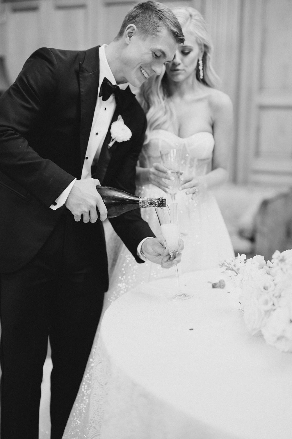 The groom pours a glass of champagne for the bride at Fountainview Mansion.