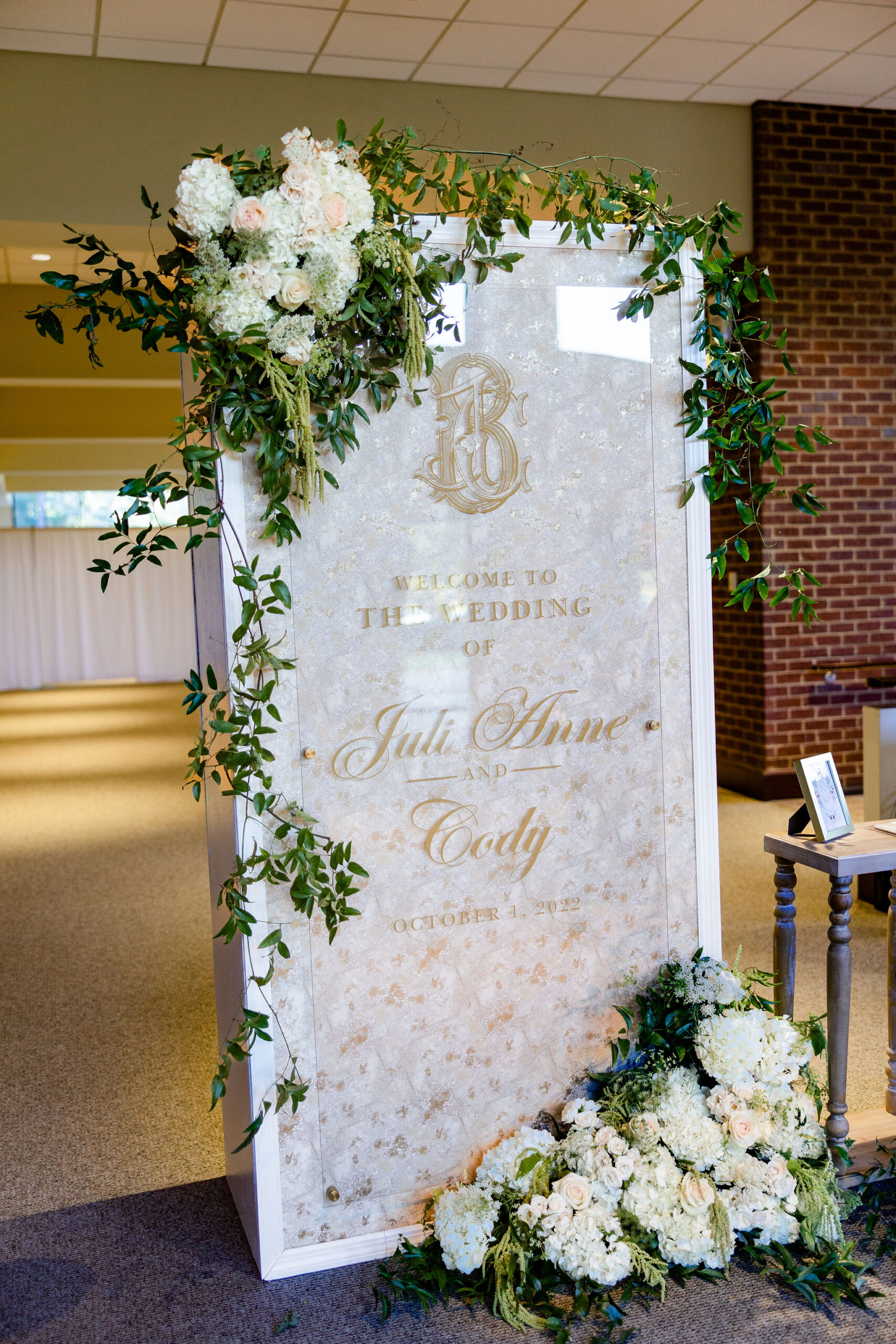 A welcome sign is decorated with white flowers for a Birmingham wedding ceremony.