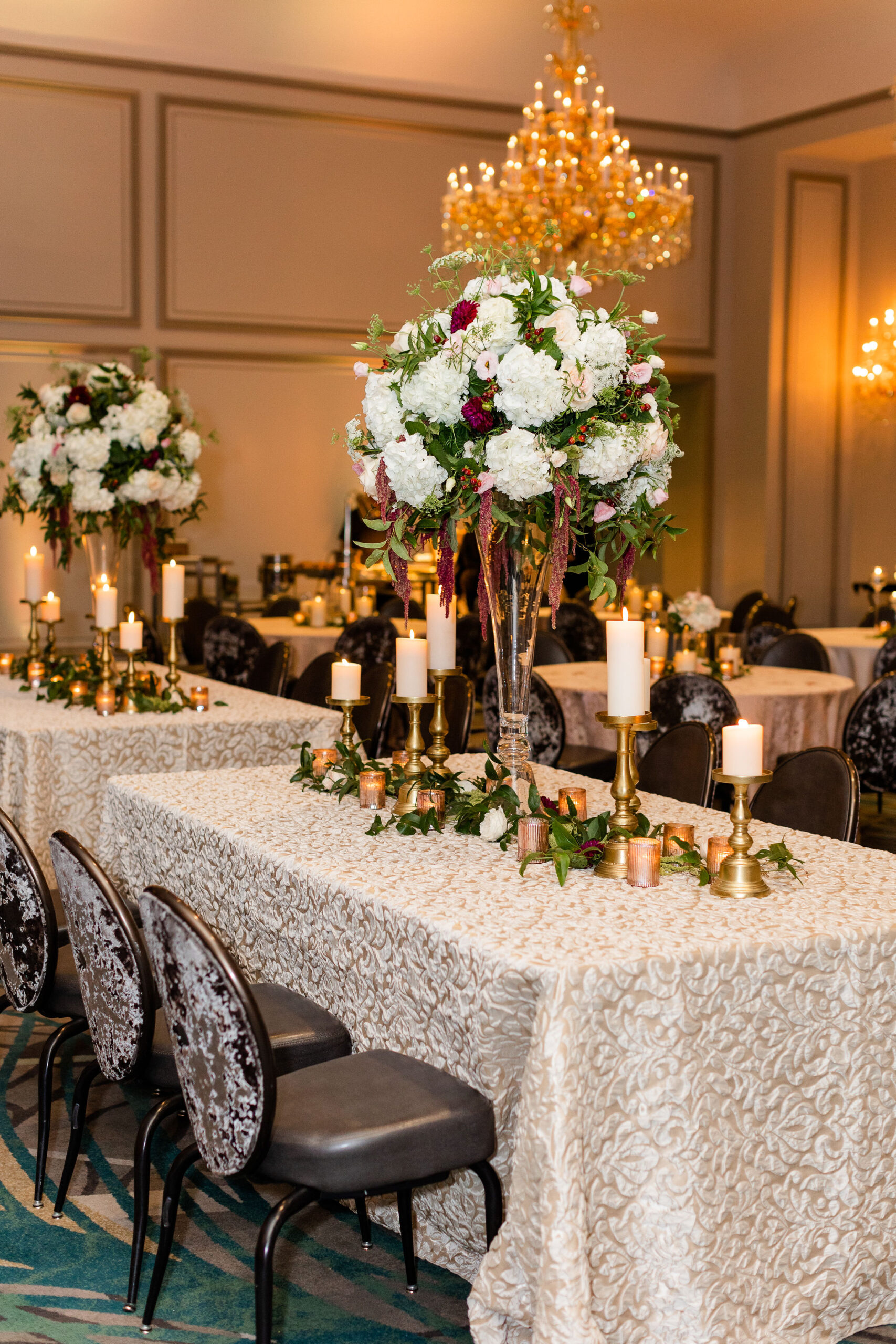 The ballroom at Grand Bohemian Hotel Mountain Brook is decorated with floral tablescapes and candles.