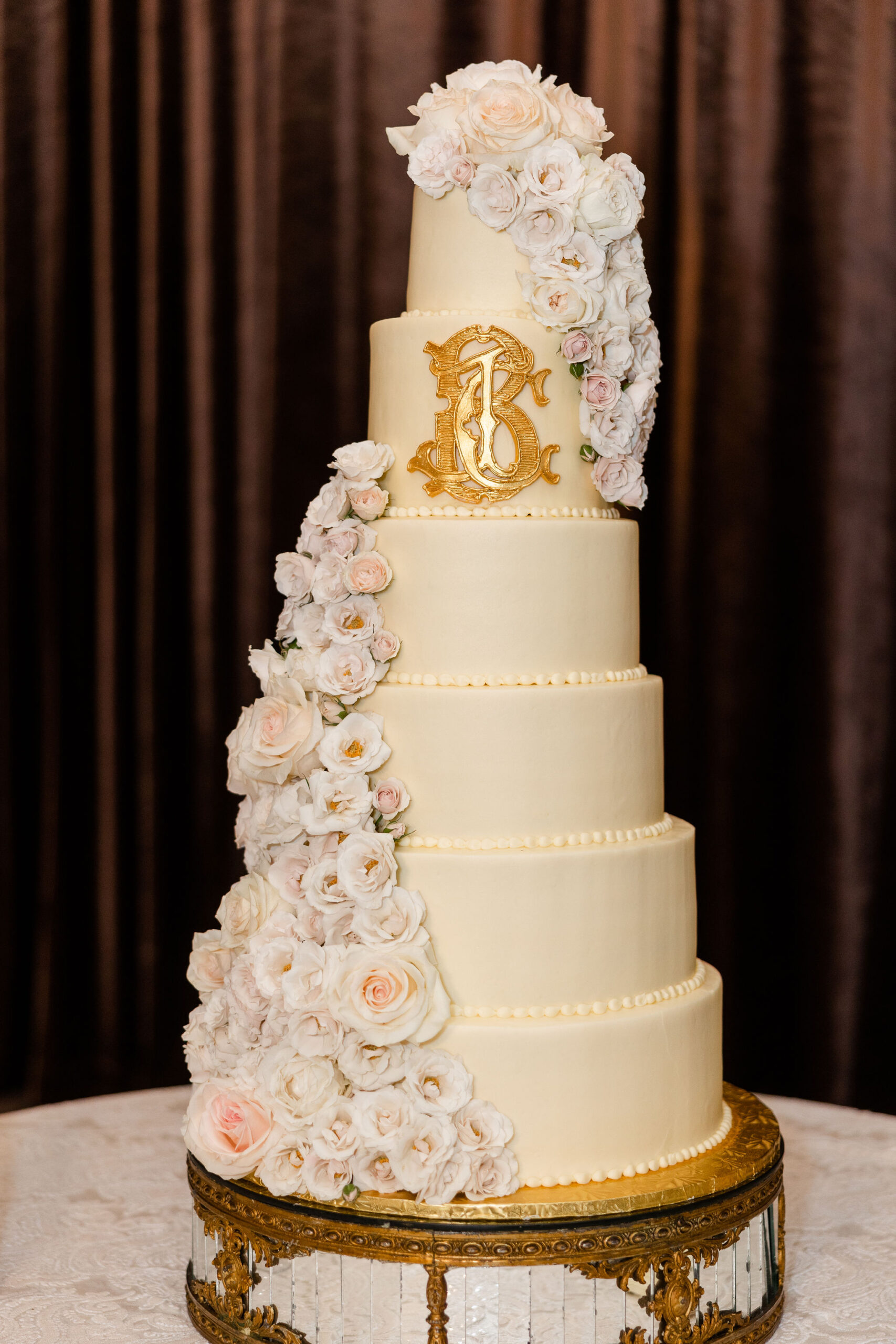 The wedding cake is decorated with dress flowers and a monogram at Grand Bohemian Hotel Mountain Brook.